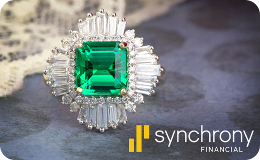 A beautiful emerald ring with the Synchrony logo next to it