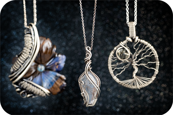 A collection of three custom wire wrapped pieces made with dendrite and boulder opal