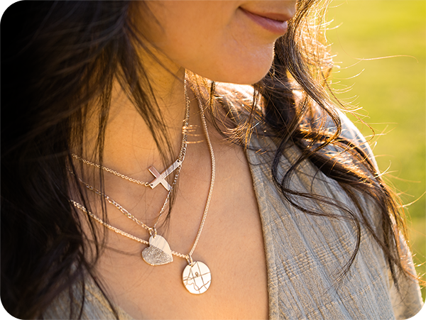 A woman wearing three layered necklaces with engraved pendants