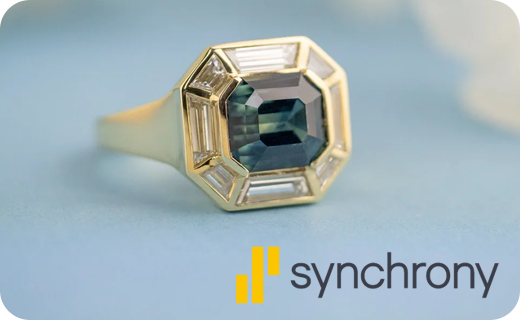 A custom ring with a parti color sapphire and the Synchrony logo next to it