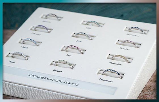 A tray of stackable bands with natural birthstone gems set in each one
