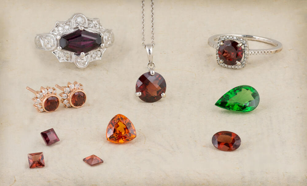 Group of garnet gemstones of various colors both loose and set in jewelry