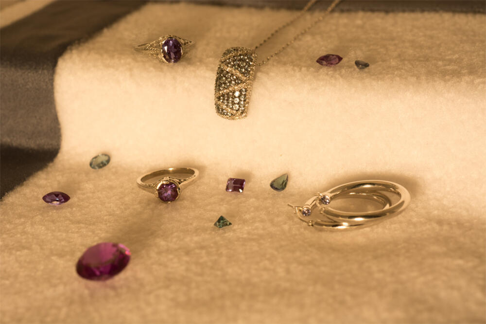 A group of alexandrite jewelry and loose gems shown in incandescent light