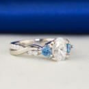 side view oval diamond with trillion aquamarine accents ring
