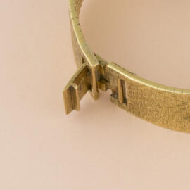 An open fold over clasp on a yellow gold bracelet