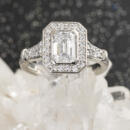 Custom emerald cut diamond halo engagement ring with engraved accents front on crystal
