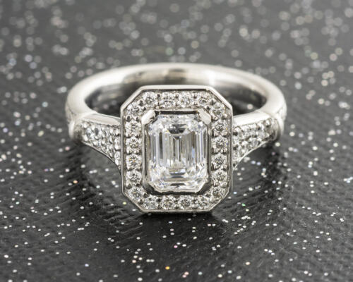 Custom emerald cut diamond halo engagement ring with engraved accents front