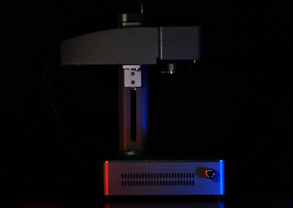 Dark picture of a laser engraver with red and blue lights on it