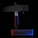 Dark picture of a laser engraver with red and blue lights on it