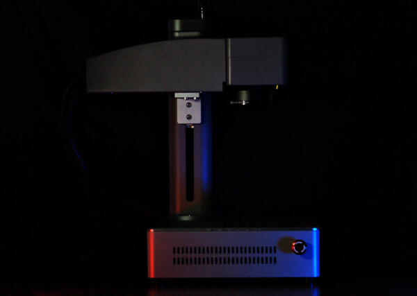 Dark picture of a laser engraver with red and blue lights on it