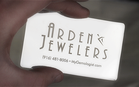 A silver business card with Arden Jewelers on one side and laser on the other
