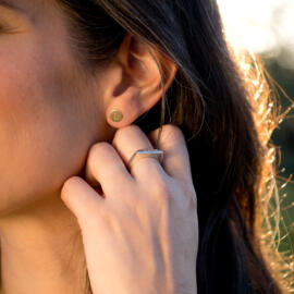 Engravable stacking silver ring next to gold disc earrings being worn