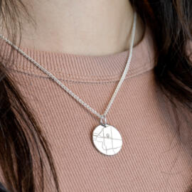 Engravable circular map pendant being worn