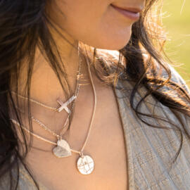 Layered chain look with three engravable pendants being worn at the same time - circle cross and heart