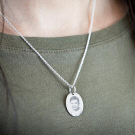 Oval engravable pendant with baby picture in silver being worn