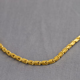 A close up shot of a yellow gold baht chain