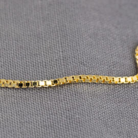 A close up shot of a yellow gold box chain