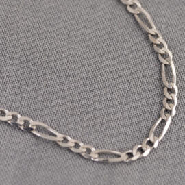 A close up of a white gold figaro chain
