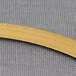 A close up shot of a yellow gold herringbone chain