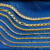 A group of yellow gold chains of different kinds of a blue background