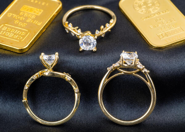 Three yellow gold engagement rings next to gold bars