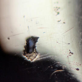 A close of view of a bit of sand embedded in some porosity in a ring