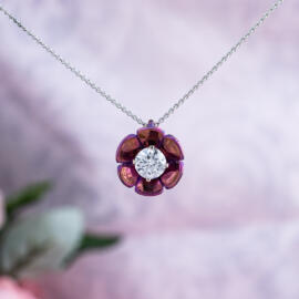 Lotus blossom pendant with magenta titanium and round lab diamond on 14k white gold chain in front of pink background