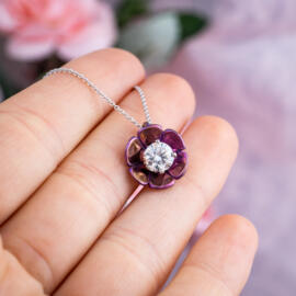 Lotus blossom pendant with magenta titanium and round lab diamond on 14k white gold chain held in hand for perspective