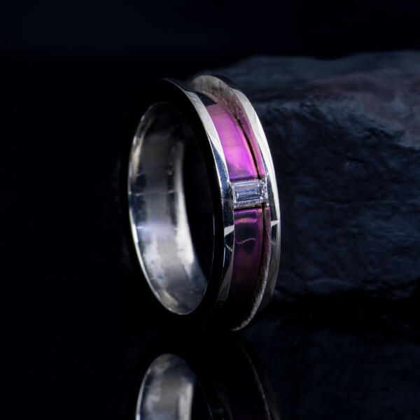 14k white gold band with channel set natural diamond accent and magenta titanium inlay in dark setting next to a rock