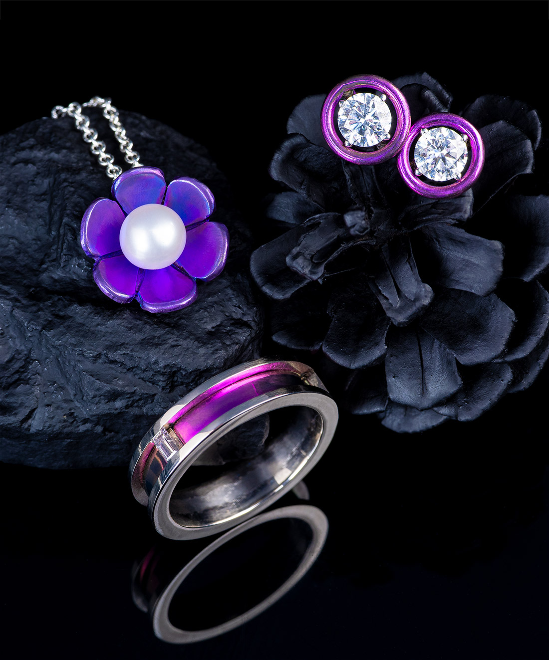 Group of brightly colored titanium jewelry pieces on a dark background