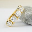 Custom yellow gold five stone diamond band resting on rock