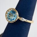 Custom blue topaz off center ring with diamond accents angled view