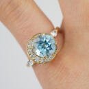 Custom blue topaz off center ring with diamond accents on finger