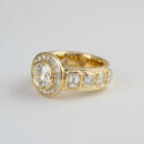 14 karat yellow gold custom diamond bezel ring with white backdrop angle view